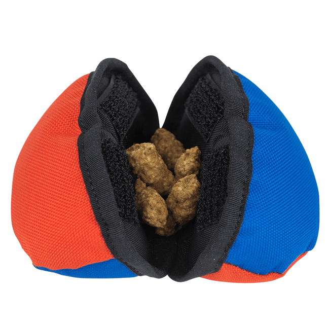 red and blue dog mesh treat dispenser with treats inside on a white background